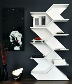 a white book shelf with books on it in a living room next to a painting