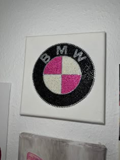 a white wall with a pink and black bmw emblem on it's left side