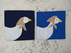 two pieces of fabric with white and blue designs on them, one has a bird in the middle