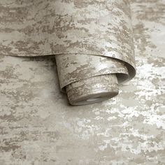 a roll of fabric on top of a wallpaper covered in grey and white paint