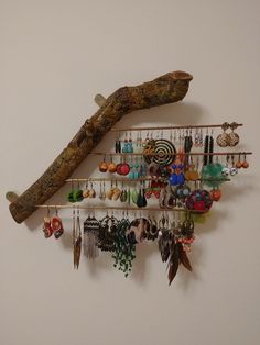 a tree branch hanging from the side of a wall with earring hooks attached to it