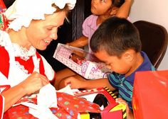 a woman and two children opening christmas presents