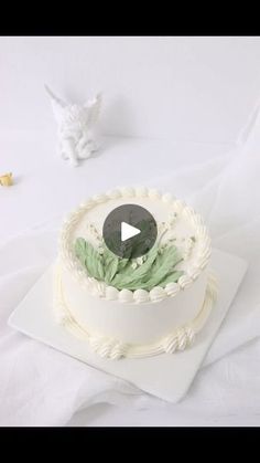 a white cake sitting on top of a table covered in frosting and green leaves