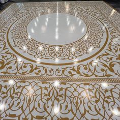 an intricately designed floor in the middle of a room with lights shining on it