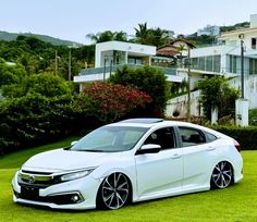 a white car parked on top of a lush green field next to a large building