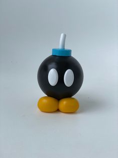 a black and yellow toy with two eyes on it's head, sitting in front of a white background