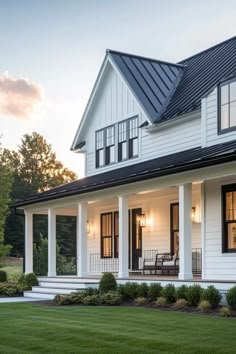 a white house with black shingles and windows on the front porch is shown at sunset