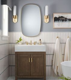 a white sink sitting under a mirror in a bathroom next to a wooden cabinet and counter