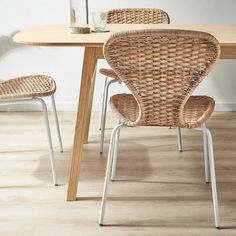 a wicker dining table with two chairs and a vase on the top one side