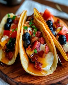 three tacos with fruit and cheese on a wooden plate