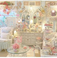 a room filled with white furniture and lots of pink flowers on the table in front of it