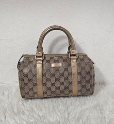 Gucci GG mini boston bag in coated canvas and gold leather trimmings. It has top leather handles, fabric lined interior, top zip closure, and gold hardware.  H - 15cm W - 24cm D - 10cm Discolouration on exterior. Creasing and ribbing on handled. Mild discolouration on wear on interior and light scuffs on edges and corners. No rips, no tears. No dustbag and no added accessories Gucci Mini, Top Handle Bags, Boston Bag, Leather Handles, Gold Leather, Leather Handle, Gold Hardware, Purses And Handbags, Top Handle