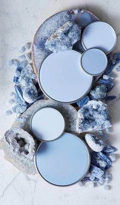 three plates with blue paint on them sitting next to some rocks and ice crystals in the middle