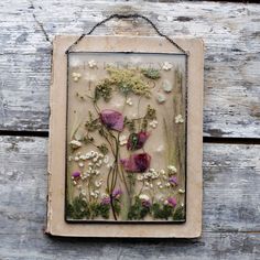 an old frame with flowers and moss on it