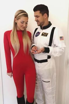 a man and woman dressed as astronauts standing next to each other in front of a door