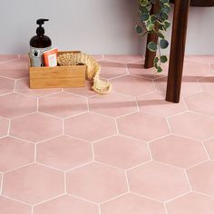 a bathroom with pink hexagonal tiles and a wooden box on the floor next to it