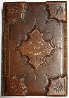 an old leather book with ornate designs on the front and back cover, in gold lettering