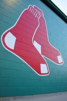 a red sox logo painted on the side of a green brick building with white trim