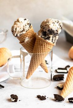 two ice cream cones with chocolate chip cookies in them on a white plate next to oreo chips