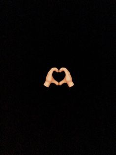 two hands making a heart shape in the dark