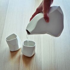 someone pours water into small cups on a table