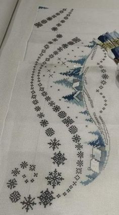 a cross - stitched tablecloth with an embroidered design on it and a paintbrush