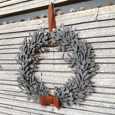 a wreath hanging on the side of a building with brown leather handles and leaves attached to it