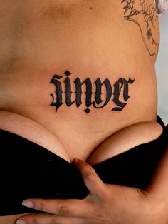 a woman's stomach with the word tattoo on her lower back and upper part