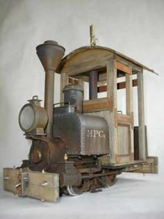 an old steam engine sitting on top of wooden pallets in front of a white wall