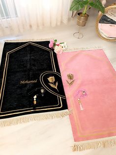 two black and pink rugs on the floor next to a mirror with flowers in it