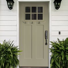 the front door of a white house with two planters