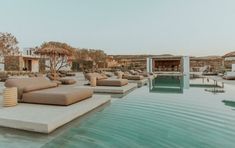 an outdoor pool with lounge chairs and umbrellas next to it in the middle of a resort