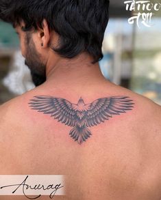 the back of a man's shoulder with an eagle tattoo on his upper arm