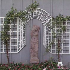 a statue in front of a building with flowers around it