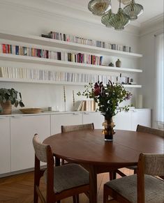 a dining room table and chairs with bookshelves in the background