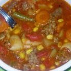 a white bowl filled with meat and vegetable soup on top of a blue table cloth