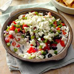 a bowl filled with lots of different types of food next to a bowl of chips