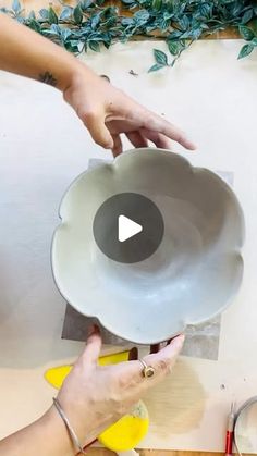 two hands are holding a white plate on a table