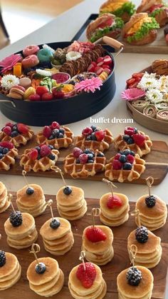 a table topped with lots of waffles covered in berries and other toppings