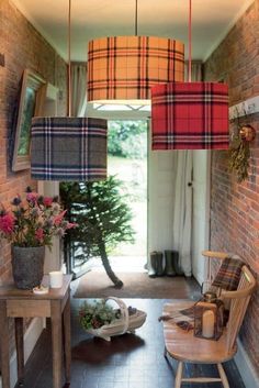 an entry way with plaid lamps hanging from the ceiling and flowers in vases on the floor