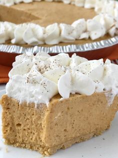 a slice of pumpkin pie with whipped cream on top and another pie in the background