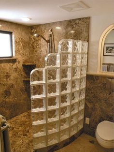 a glass block shower in a bathroom next to a toilet