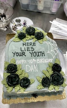 there is a birthday cake that has been decorated with black roses and words on it