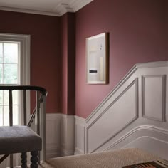 a room with red walls and white trim on the wall, along with a gray bench