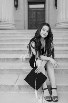 a young woman sitting on the steps with her graduation cap and book in her hand