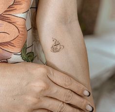 a woman with a tattoo on her arm holding a coffee cup in her right hand