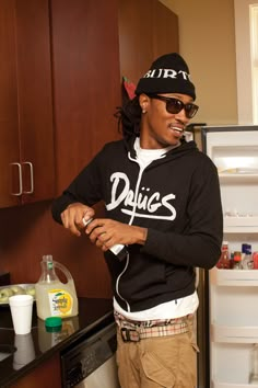 a man standing in front of an open refrigerator holding a wine bottle and looking at the camera