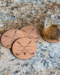 four wooden coasters sitting on top of a granite counter next to a glass of wine