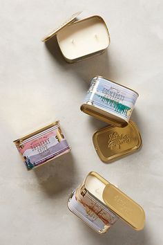 four small tins filled with different types of gold and silver items on a white surface