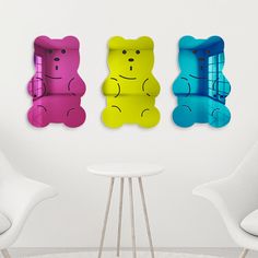 three colorful teddy bears sitting next to each other in front of a white table and chairs